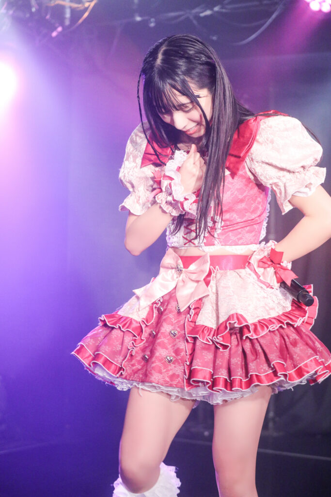 embellir(あんべりー)の水野ひなたちゃんをライブ中に撮影した写真。
胸に手を当て少し俯くポーズ。とても優しくほほえんでいる。
2025年11月22日 Zirco Tokyo SYNC FESTAにて撮影。