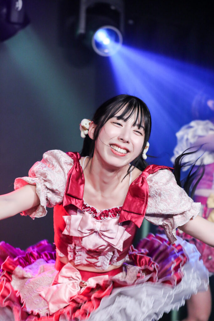 embellir(あんべりー)の水野ひなたちゃんをライブ中に撮影した写真。ターンした瞬間を捉えたので髪やスカートがふわっと浮いている。とても優しい笑顔。
2025年11月29日　GOTANDA G4　UK祭にて撮影。