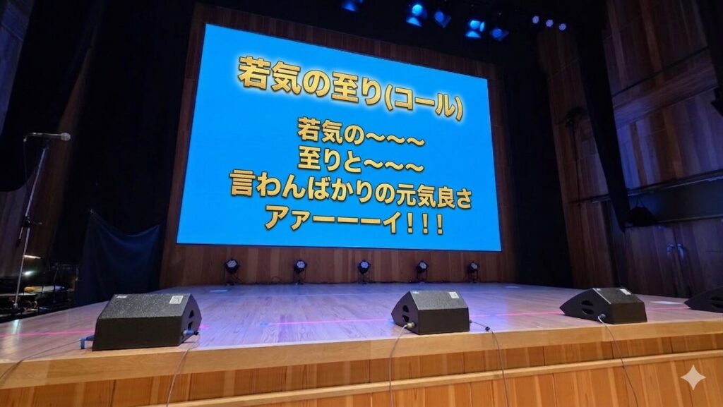 ステージのバックスクリーンにコールのテキストが映し出されている。以下コールの内容。 若気の至り(コール) 若気の～～～ 至りと～～～ 言わんばかりの元気良さ アァーーーイ！！！