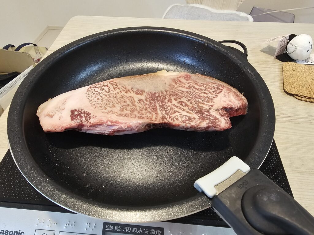 肉ガチャで届いたステーキをフライパンに乗せている様子。