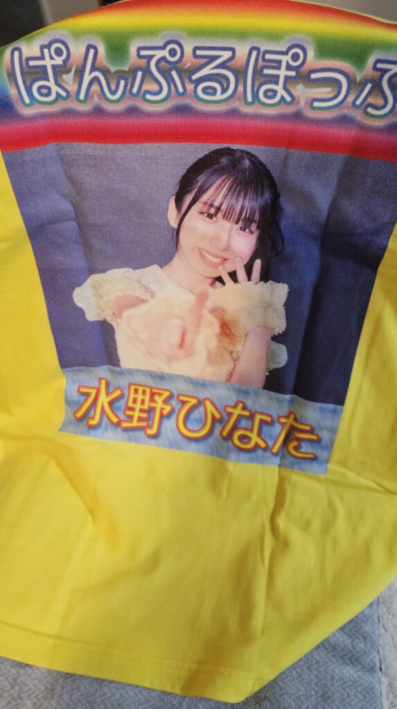 UP-Tから届いた推しTシャツ背中側。黄色のTシャツ素体に「ぱんぷるぽっぷ　水野ひなた」というテキストと、真ん中に黄色衣装を着たひなたちゃんがカメラをツンツンしている仕草の写真が入っている。