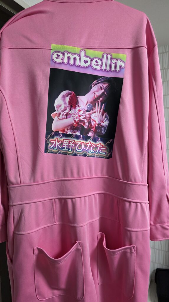 ピンクのつなぎの背中側にアイロンプリントでembellir(あんべりー)の水野ひなたちゃんの写真を貼りつけた様子。