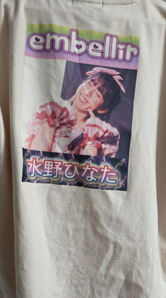 ピンクのTシャツの背中側にアイロンプリントでembellir(あんべりー)の水野ひなたちゃんの写真を貼りつけた様子。