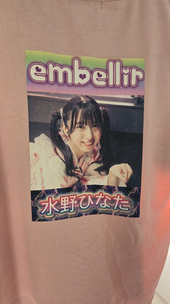 ピンクのTシャツの背中側にアイロンプリントでembellir(あんべりー)の水野ひなたちゃんの写真を貼りつけた様子。
