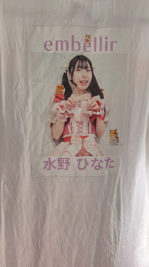 embellir(あんべりー)の水野ひなたちゃんに驚くハムスターのミーム画像の顔を再現してもらい、それにグループ名と名前を追加して背中側にアイロンプリントしたハムスターTシャツ。