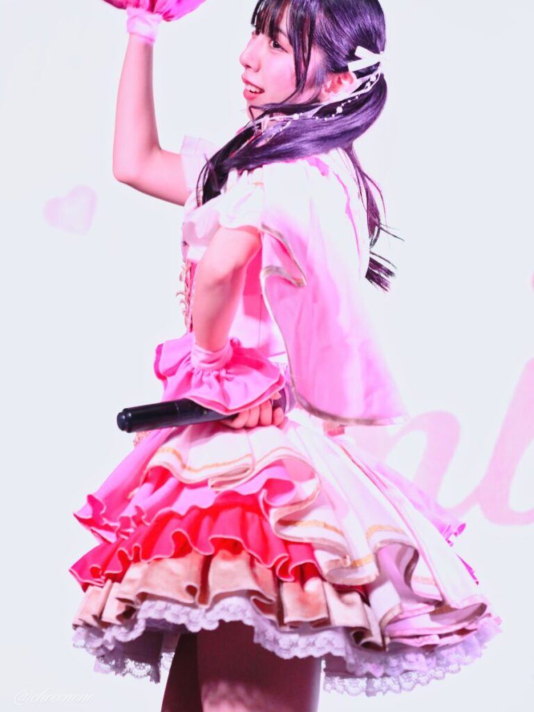 embellir(あんべりー)の水野ひなた(みずのひなた)ちゃんを最前列上手2番辺りからライブ中に撮影した写真。ひなたちゃんはピンクの襷衣装。ツインテールに白いリボンとパールの飾りを着けている。 ダンスの最中、髪や衣装の飾りがダイナミックに動いていてかっこいい。 2026年3月3日SHIBUYA ONE5　embellir presents ひなまつりにて撮影。