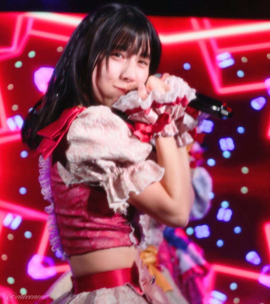 embellir(あんべりー)の水野ひなた(みずのひなた)ちゃんを最前列0番の位置からライブ中に撮影した写真。 ひなたちゃんはストレートヘアーをベースに一束髪を編んでいる。 ほっぺたをぷくっとさせつつ口元でグーを作ってぶりっこポーズ。可愛い 2026年3月15日中野坂上S.U.B Tokyo　妃Fesにて撮影。