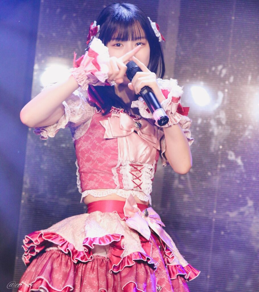 embellir(あんべりー)の水野ひなた(みずのひなた)ちゃんを最前列下手1番の位置からライブ中に撮影した写真。 毛先を巻いて赤いリボンで飾り付けている。 顔の前に指でバッテンを作っている。 2026年3月10日GOTANDA G4　無銭ぷろじぇくと!!にて撮影