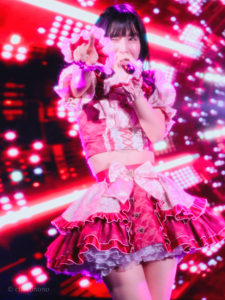 embellir(あんべりー)の水野ひなた(みずのひなた)ちゃんを最前列0番の位置からライブ中に撮影した写真。 ひなたちゃんはストレートヘアーをベースに一束髪を編んでいる。 ベリーベリーの「運命的」の歌詞に合わせてフロアの後方を指さしながらウィンクしている。 2026年3月15日中野坂上S.U.B Tokyo　妃Fesにて撮影。