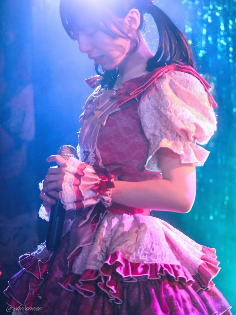 embellir(あんべりー)の水野ひなた(みずのひなた)ちゃんを最前列0番の位置からライブ中に撮影した写真。 ひなたちゃんはこの日の主役の七瀬ましろちゃんをリスペクトして先端をやや巻いたツインテールをしている。 しっちゃかめっちゃかパラダイスの冒頭少し俯いて歌い出しを待機している。 2026年3月22日　神田CLUB F♯　七瀬ましろ生誕祭2026 ～ねぇねぇ教えて！ましろ、今日も可愛い？～にて撮影。