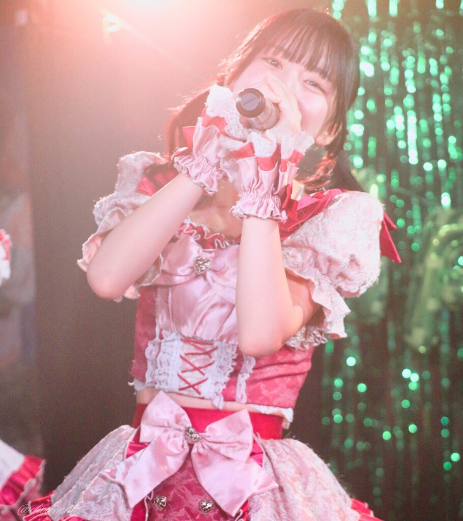 embellir(あんべりー)の水野ひなた(みずのひなた)ちゃんを最前列0番の位置からライブ中に撮影した写真。 ひなたちゃんはこの日の主役の七瀬ましろちゃんをリスペクトして先端をやや巻いたツインテールをしている。 MC中、マイクを構えつつこちらをまっすぐ見つめてくれている。 2026年3月22日　神田CLUB F♯　七瀬ましろ生誕祭2026 ～ねぇねぇ教えて！ましろ、今日も可愛い？～にて撮影。