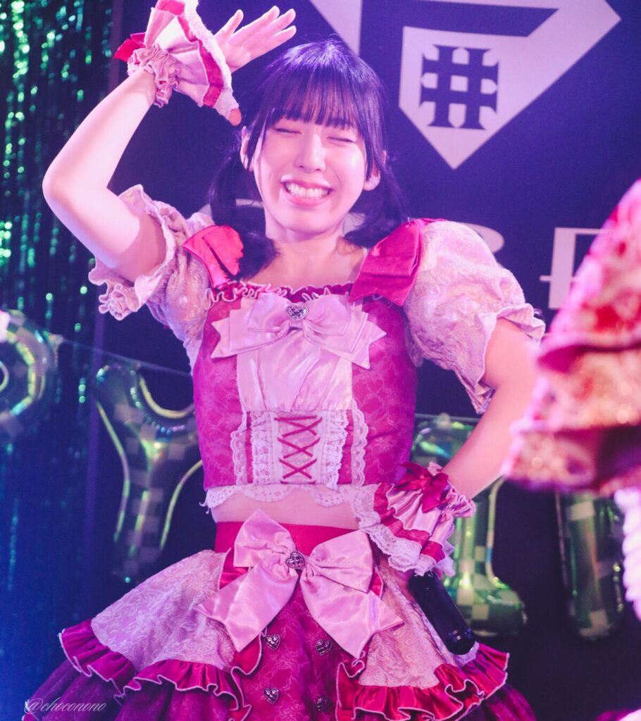 embellir(あんべりー)の水野ひなた(みずのひなた)ちゃんを最前列0番の位置からライブ中に撮影した写真。 ひなたちゃんはこの日の主役の七瀬ましろちゃんをリスペクトして先端をやや巻いたツインテールをしている。 ときめきフルスロットルの「君を見つけたの」の歌詞に合わせて手で頭の上にひさしを作って「見つけた！」のポーズ。 2026年3月22日　神田CLUB F♯　七瀬ましろ生誕祭2026 ～ねぇねぇ教えて！ましろ、今日も可愛い？～にて撮影。