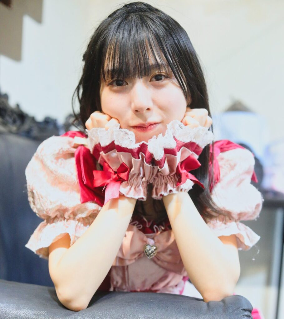 embellir(あんべりー)の水野ひなた(みずのひなた)ちゃんを特典会で撮らせてもらったソロショット写真。 ひなたちゃんはストレートヘアーに編みたらしをしている。 ソファーの肘置きに両肘を乗せて頬杖をついている。 2026年3月28日中野坂上S.U.B Tokyo Tune JACKにて撮影。