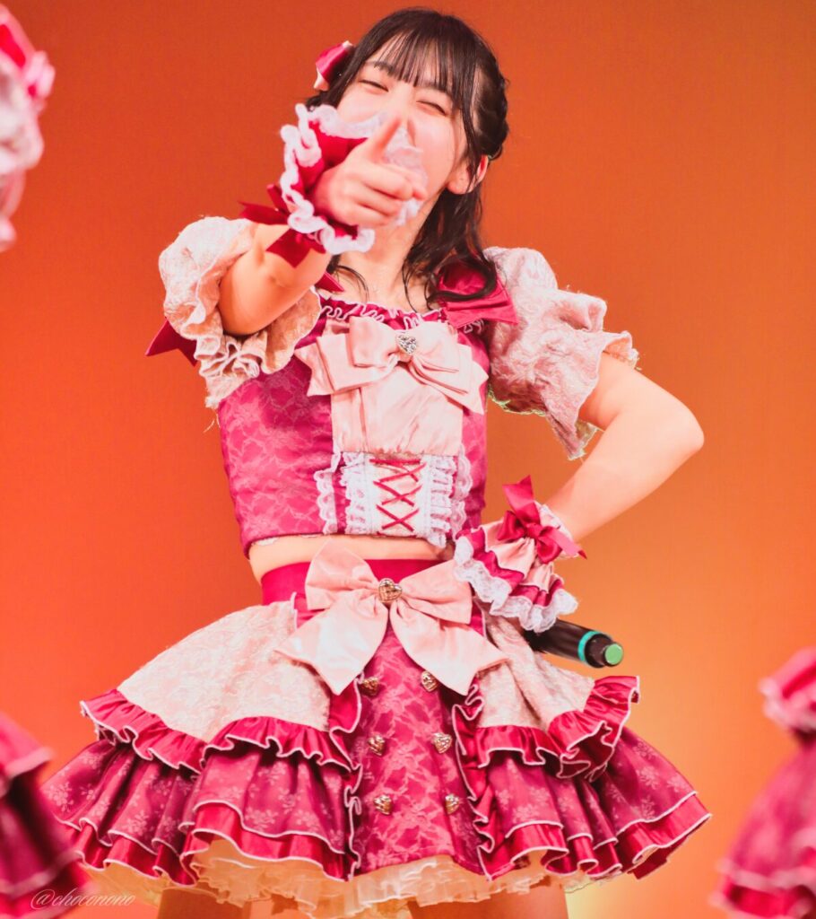 embellir(あんべりー)の水野ひなた(みずのひなた)ちゃんを最前列0番の位置からライブ中に撮影した写真。 ひなたちゃんは編み込みにくるみちゃんヘアー。衣装のイメージにぴったりなベリーカラーのリボンをしている。 ときめきフルスロットルの「君を見つけたの」の歌詞に合わせてこちらを指さしてくれている。 2026年4月4日なかのZERO小ホール IDOL SODA Stream!!にて撮影。