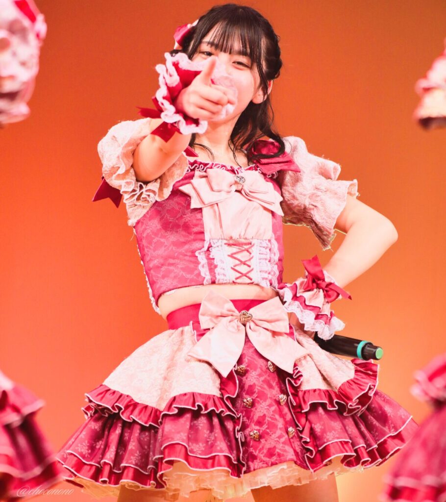 embellir(あんべりー)の水野ひなた(みずのひなた)ちゃんを最前列0番の位置からライブ中に撮影した写真。 ひなたちゃんは編み込みにくるみちゃんヘアー。衣装のイメージにぴったりなベリーカラーのリボンをしている。 ときめきフルスロットルの「君を見つけたの」の歌詞に合わせてこちらを指さしてくれている。 2026年4月4日なかのZERO小ホール IDOL SODA Stream!!にて撮影。