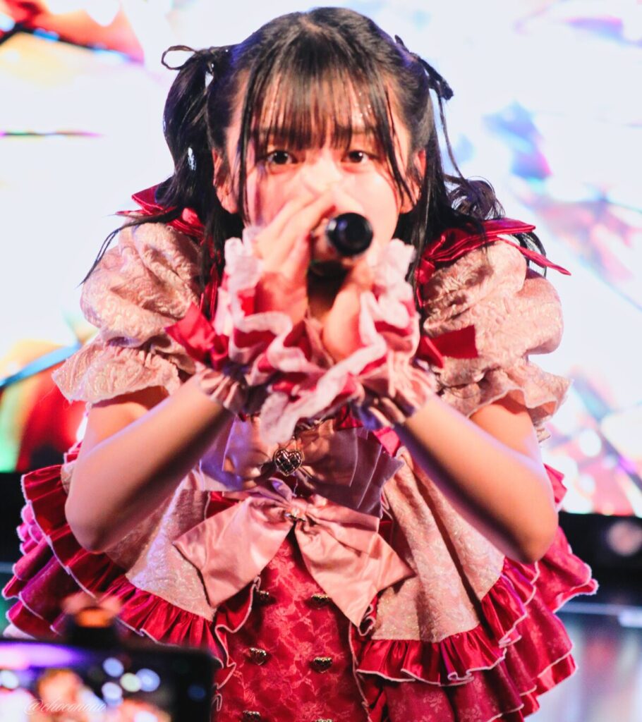 embellir(あんべりー)の水野ひなた(みずのひなた)ちゃんを最前列0番の位置からライブ中に撮影した写真。 ひなたちゃんはハーフツインの根元を輪っかに結んでハムちゃんヘアー。 フツーに奇跡!!の「出会えて良かった ありがとう」の歌詞に合わせておじぎをしながらこちらを見つめてくれている。 2026年4月5日中野坂上S.U.B Tokyo 妃Fesにて撮影。