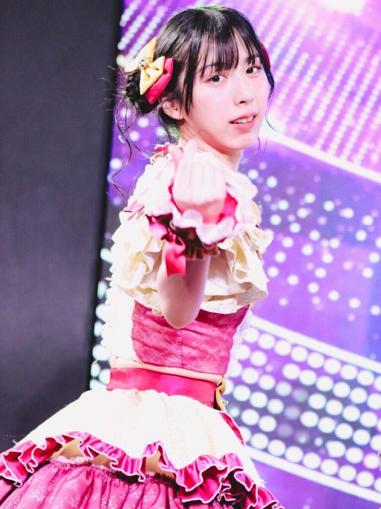 embellir(あんべりー)の水野ひなた(みずのひなた)ちゃんを最前列下手2番あたりからライブ中に撮影した写真 ひなたちゃんは普段と衣装を交換してきいろ色の衣装。お団子からちょろちょろとしっぽが出ているような髪型。 振り向きざまに指ハートをこちらに飛ばしてくれている。 2026年4月9日SHIBUYA ONE5 embellir主催ライブにて撮影。