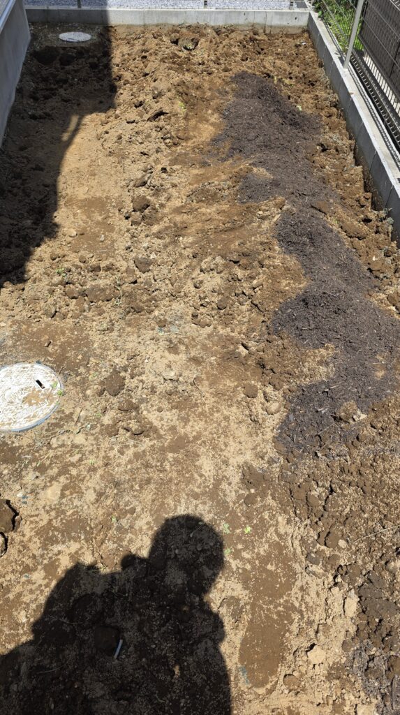 掘り返した土の山にバーク入り腐葉土を混ぜ込んだ状態の庭の様子。