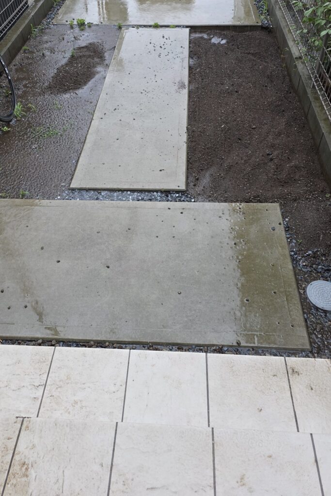 玄関前の石畳の両脇にある土の様子。大雨で左側は全体が水たまりになっている。対して右側はほとんど水たまりにならず、水がしっかりと流れていることが分かる。