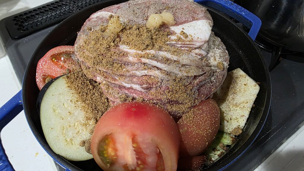 キャベツの嵩が減り、なす、ラム肉、トマト、塩こしょう、カレーパウダー、にんにくを追加した様子。