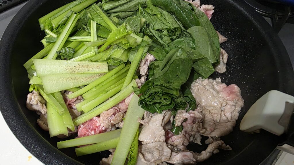 豚肉と小松菜をフライパンで炒めている様子