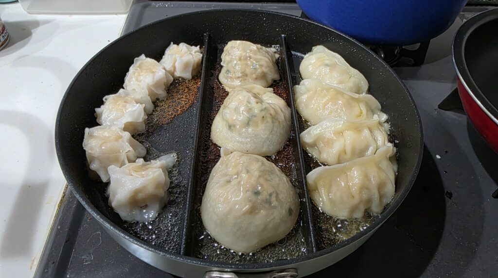 仕切りフライパンの上で調理が完了したえびシューマイ、肉マンドゥ、焼き餃子
