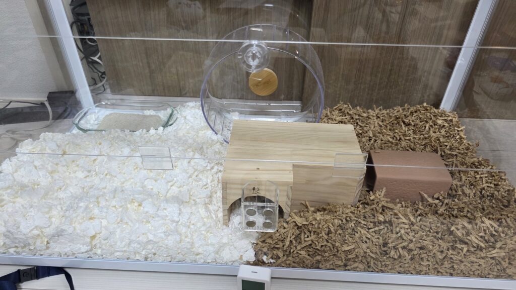ケージ内の様子。右半分と左半分で別々の床材を敷き、届いた隠れ家やテラコッタトンネル、100均で買ってきた耐熱皿にトイレ砂を入れたトイレなどを設置してひまわりちゃんのお迎え準備を済ませた状態。