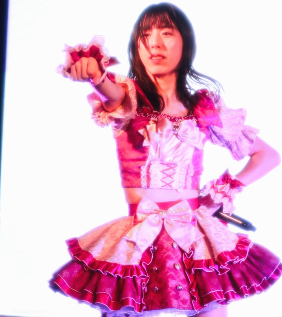 embellir(あんべりー)の水野ひなた(みずのひなた)ちゃんを最前列0番の位置からライブ中に撮影した写真。 ひなたちゃんはストレートヘアーをベースに一束髪を編んでいる。 推し☆きゅるるるるんの「最高の推しだ」の歌詞に合わせて拳を前に突き出している。 2026年3月15日中野坂上S.U.B Tokyo　妃Fesにて撮影。