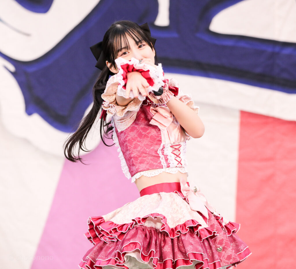 embellir(あんべりー)の水野ひなた(みずのひなた)ちゃんをライブ中に三列目真ん中あたりから撮影した写真。 ツインテールに黒い大きなリボン。 ベリーベリーの「可愛いが欲しいの~」の歌詞に合わせてこちらを見ながら手をさしのべてくれている。 2026年1月25日上野水上音楽堂 超FREE BOMBER!!にて撮影