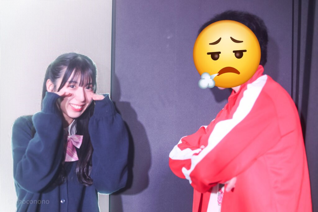 embellir(あんべりー)の水野ひなた(みずのひなた)ちゃんと特典会で撮ってもらったツーショット写真。ひなたちゃんは制服にセーター、私は赤のジャージ上下でごくせんのヤンクミ風。私の生徒指導でひなたちゃんが泣いているシチュエーション。にこにこうそ泣きしていて可愛い。 2026年2月13日SHIBUYA ONE5　embellir presents VALENTINE LIVEにて撮影。