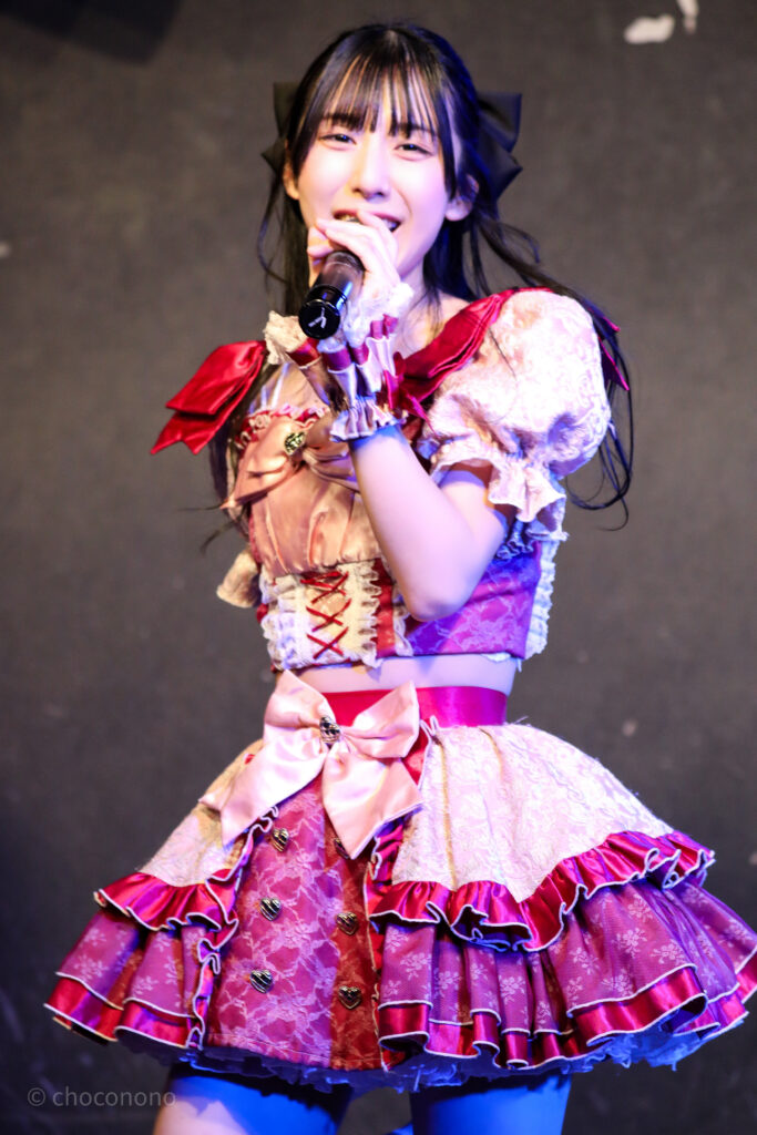 embellir(あんべりー)の水野ひなた(みずのひなた)ちゃんを最前列0番の位置からライブ中に撮影した写真。マイクを構えてにこにこと歌唱している。 2026年2月19日GOTANDA G6　無銭ぷろじぇくと!!にて撮影。