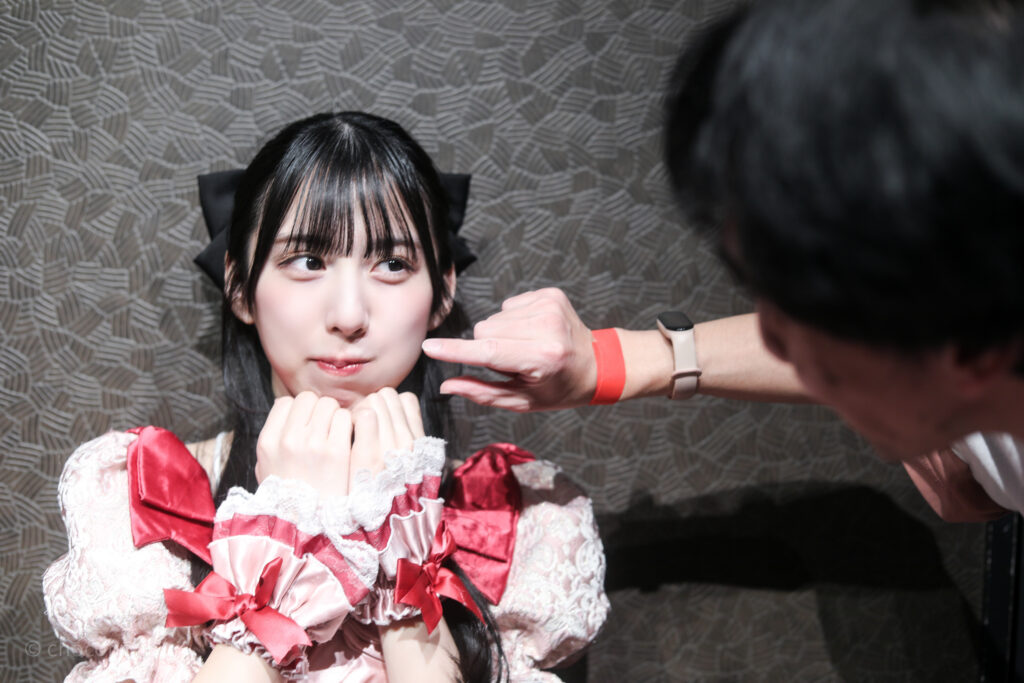 embellir(あんべりー)の水野ひなた(みずのひなた)ちゃんと特典会で撮ってもらったツーショット写真。 ひなたちゃんのほっぺたをつまもうとしている。ひなたちゃんはつままれる側のほっぺをぷくっと膨らませて「待ち」の表情でとても可愛い。 2026年2月19日GOTANDA G6　無銭ぷろじぇくと!!にて撮影。