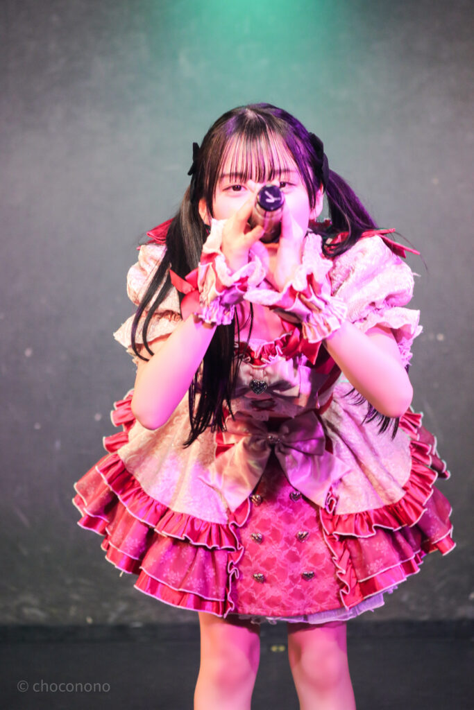 embellir(あんべりー)の水野ひなた(みずのひなた)ちゃんを最前列0番の位置からライブ中に撮影した写真。 黒いリボンでツインテールにしている。 フツーに奇跡!!の「出会えてよかったありがとう」の歌詞に合わせてお辞儀をしている。 2026年2月21日GOTANDA G6　無銭ぷろじぇくと!!にて撮影。