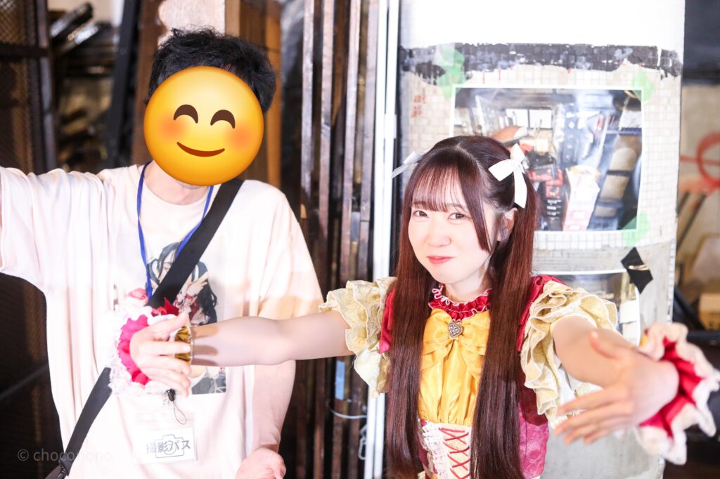 embellir(あんべりー)の泡沫あおい(うたかたあおい)ちゃんと特典会で撮ってもらったツーショット写真。 あおいちゃんはツインテールに白いリボンを着けている。 あおいちゃんが抱きしめるようなジェスチャーをして「包容力」を発揮している。 2026年2月23日東京キネマ倶楽部　IDOL大博覧会にて撮影。