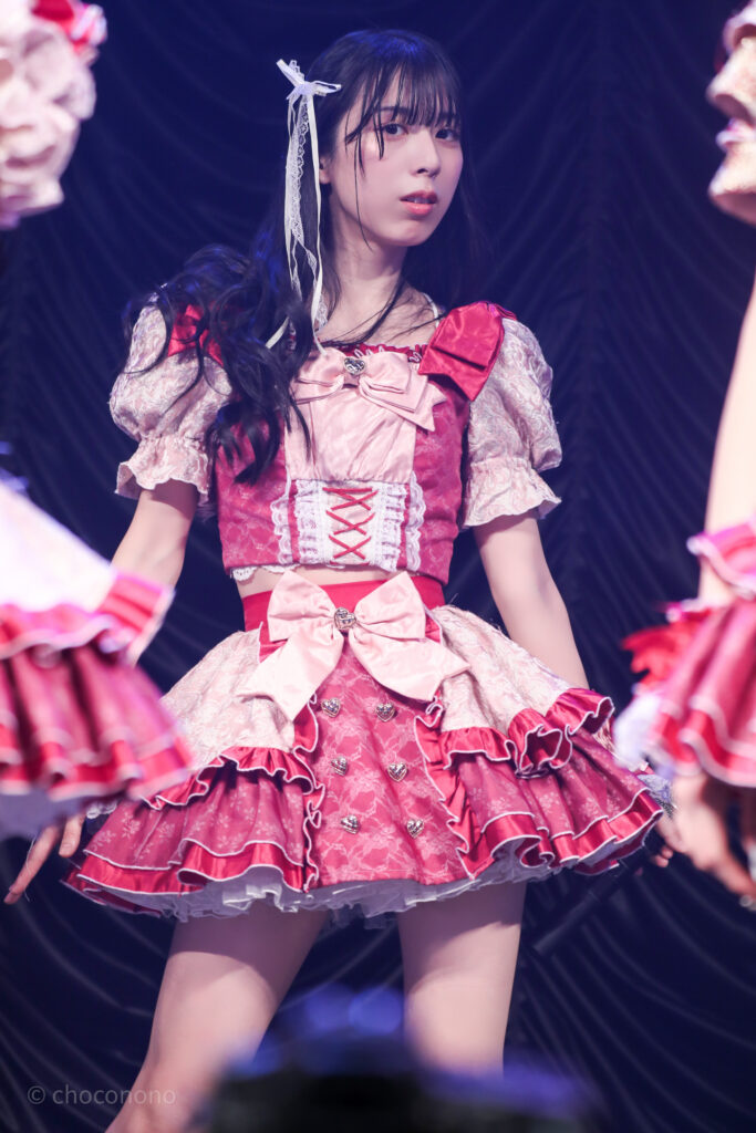 embellir(あんべりー)の水野ひなた(みずのひなた)ちゃんを最前列0番の位置からライブ中に撮影した写真。 ひなたちゃんは巻いた髪に白いリボンを着けている。 ときめきフルスロットルの「諦めたその瞬間」の歌詞の部分でこちらに気付いたように視線を向けてくれている。 2026年2月23日東京キネマ倶楽部　IDOL大博覧会にて撮影。