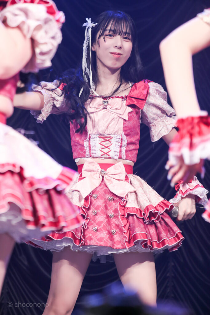 embellir(あんべりー)の水野ひなた(みずのひなた)ちゃんを最前列0番の位置からライブ中に撮影した写真。 ひなたちゃんは巻いた髪に白いリボンを着けている。 ときめきフルスロットルの「諦めたその瞬間」の歌詞の部分でこちらに気付いたように視線を向けてくれている。 2026年2月23日東京キネマ倶楽部　IDOL大博覧会にて撮影。