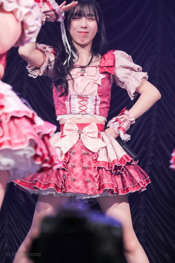 embellir(あんべりー)の水野ひなた(みずのひなた)ちゃんを最前列0番の位置からライブ中に撮影した写真。 ひなたちゃんは巻いた髪に白いリボンを着けている。 ときめきフルスロットルの「君を見つけたの」の歌詞の部分で手でひさしを作りながらにっこりとこちらを見つめてくれている。 2026年2月23日東京キネマ倶楽部　IDOL大博覧会にて撮影。