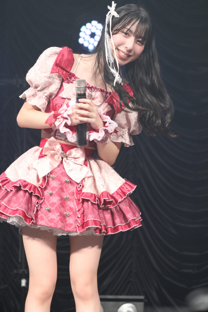 embellir(あんべりー)の水野ひなた(みずのひなた)ちゃんを最前列0番の位置からライブ中に撮影した写真。 MC中、こちらをのぞき込むようにしていたずらっぽく微笑んでいる。 2026年2月23日　東京キネマ倶楽部　IDOL大博覧会にて撮影