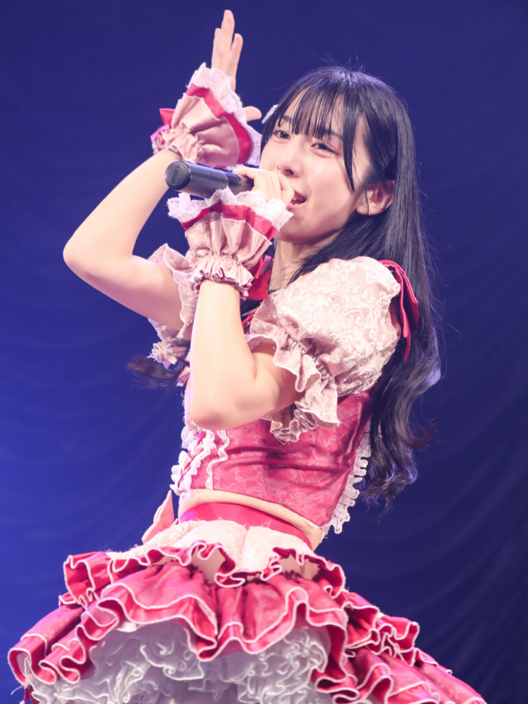 embellir(あんべりー)の水野ひなた(みずのひなた)ちゃんを最前列0番の位置からライブ中に撮影した写真。 手を王冠のようにして顔の横に構えながら歌唱している。 2026年2月23日　東京キネマ倶楽部　IDOL大博覧会にて撮影