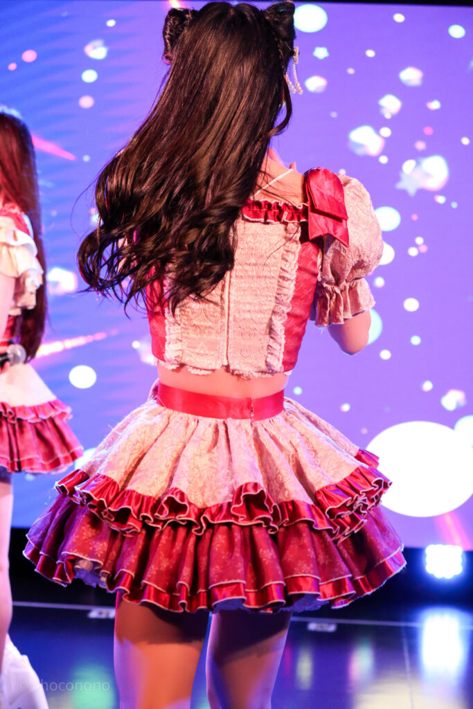 embellir(あんべりー)の水野ひなた(みずのひなた)ちゃんを最前列0番の位置から撮影したライブ写真。 ひなたちゃんは髪で猫耳を作っている。 後ろ姿。ターン直後で髪が左に流れている。 2026年2月22日中野坂上S.U.B Tokyo　妃Fesにて撮影。