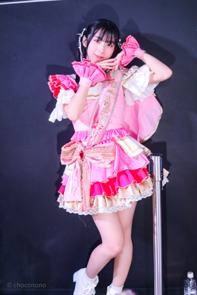 embellir(あんべりー)の水野ひなた(みずのひなた)ちゃんを特典会で撮らせてもらったソロショット写真。 ひなたちゃんはツインテールに白のリボン、姉妹グループ瞬きもせずの襷衣装のピンクを着ている。今は卒業してしまった元推しメン、琴音ゆあちゃんが当時着ていたもの。 モデルさんのようなポーズ。可愛い。 2026年3月3日SHIBUYA ONE5　embellir presentsひなまつりにて撮影。