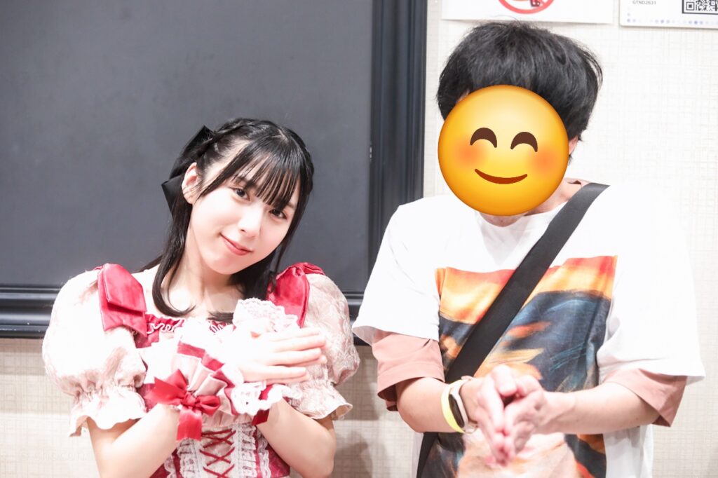 embellir(あんべりー)の水野ひなた(みずのひなた)ちゃんと特典会で撮ってもらったツーショット写真。 ひなたちゃんは編み込みに黒いリボンを着けている。 魚の日という事で二人でお魚さんポーズ。 2026年3月7日GOTANDA G6　無銭ぷろじぇくと!!にて撮影。