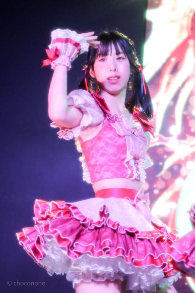 embellir(あんべりー)の水野ひなた(みずのひなた)ちゃんを最前列下手2番あたりから撮ったライブ写真。 真ん中あたりでツインテールにして赤と青のリボンで結んでいる。 顔の横でポーズを決めた指先が綺麗にそろっている。 2026年3月14日SHIBUYA ONE5　遥乃ももか×恋羽あゆうおたんじょうびかいにて撮影