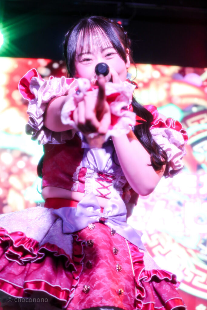 embellir(あんべりー)の甘夏あも(あまなつあも)ちゃんを最前列下手2番あたりから撮ったライブ写真。 ツインテールを赤と青のリボンで結んでいる。 こちらを真っ直ぐ見つめながら指さしてくれている。 2026年3月14日SHIBUYA ONE5　遥乃ももか×恋羽あゆうおたんじょうびかいにて撮影