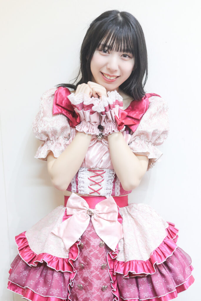 embellir(あんべりー)の水野ひなた(みずのひなた)ちゃんを特典会で撮らせてもらったソロショット写真。 ひなたちゃんはストレートヘアーをベースに、髪を一束編んでいる。 こちらを見つめながら愛嬌を振りまいている。可愛い。 2026年3月15日中野坂上S.U.B Tokyo　妃Fesにて撮影。