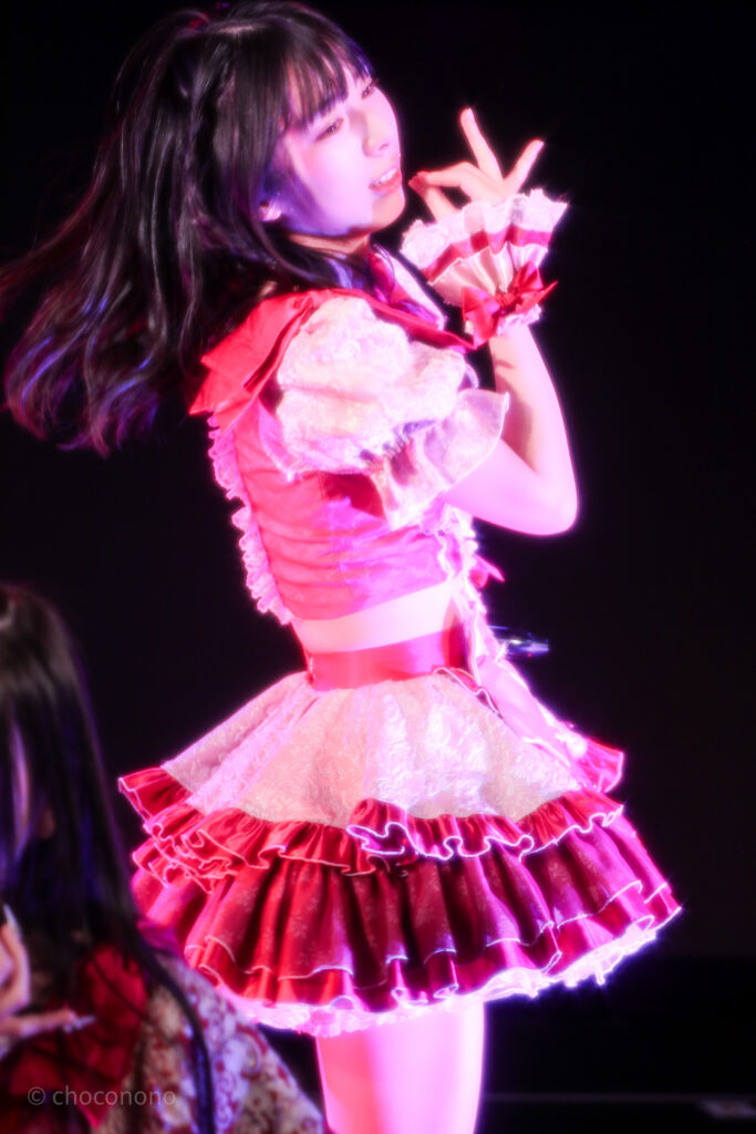 embellir(あんべりー)の水野ひなた(みずのひなた)ちゃんを最前列0番の位置からライブ中に撮影した写真。 ひなたちゃんはストレートヘアーをベースに一束髪を編んでいる。 ベリーベリーの曲中、木の実をつまんで食べるポーズ。 2026年3月15日中野坂上S.U.B Tokyo　妃Fesにて撮影。