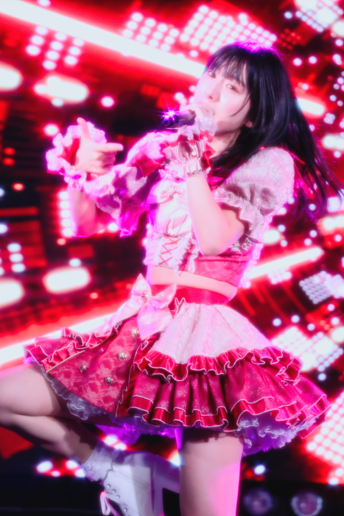 中野坂上S.U.B Tokyoでembellir（あんべりー）の水野ひなた（みずのひなた）ちゃんをEOS 5D Mark IVとEF70-300mm（120mm）にクロスフィルターを付けて縦位置で撮ったライブ写真。赤いLEDスクリーンを背景に片足を上げて指差しポーズをし、マイクで光が星形に輝いている。1/200、F4.5、ISO 3200。