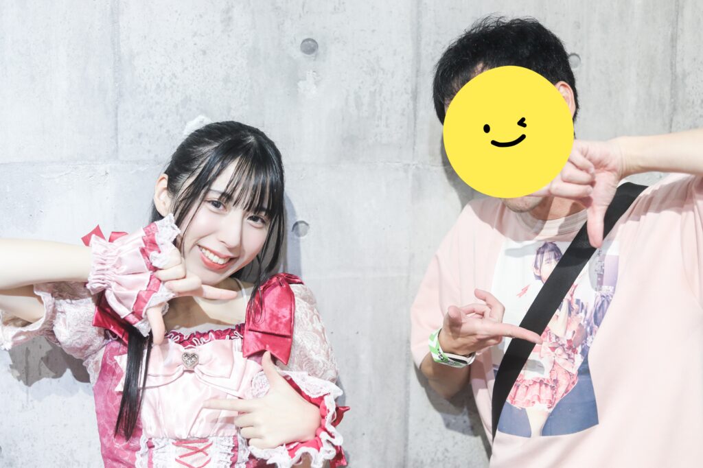 embellir(あんべりー)の水野ひなたちゃんと特典会で撮ってもらったツーショット写真。
二人とも胸の前で四角を作って「シャッターチャンス」ポーズをしている。
ひなたちゃんの笑顔がとても優しい。
心の中にぽかぽかとした「ひなた」を作ってくれる笑顔。
2025年12月4日　渋谷VIDENT　ライブジムにて撮影。