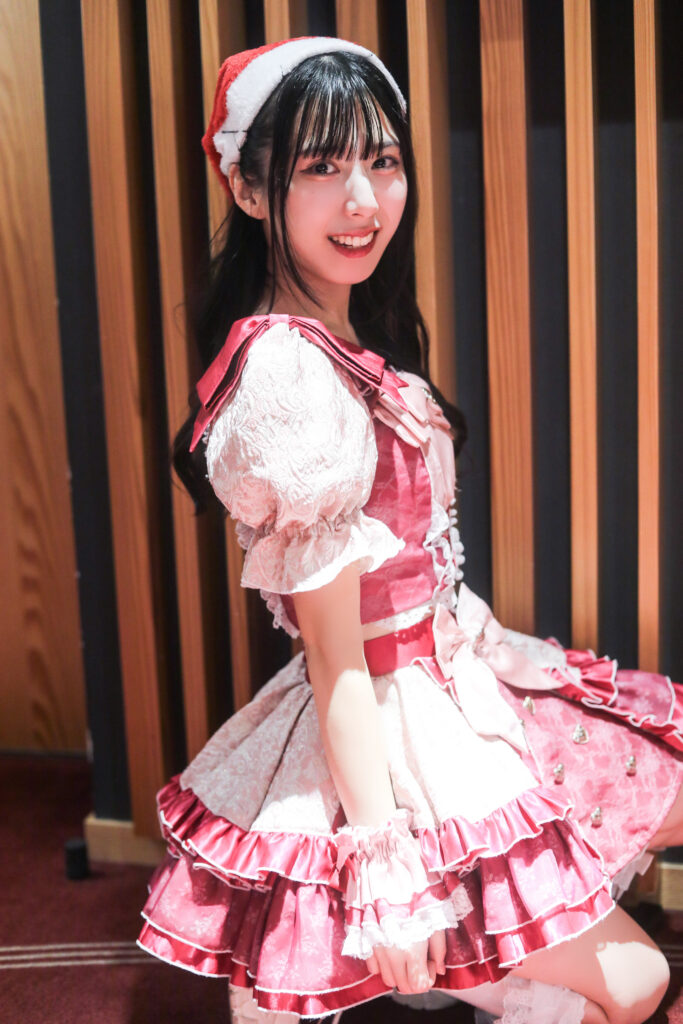 embellir(あんべりー)の水野ひなたちゃんを特典会で撮らせてもらったソロショット写真。
この日はクリスマスイベントということでひなたちゃんはサンタの帽子をかぶっている。
プレイフルという曲の「振り向いてくれる？」という歌詞のところで振り向くポーズを再現している。
2025年12月14日　としま区民センター多目的ホール　IDOL SODA Stream!!にて撮影。