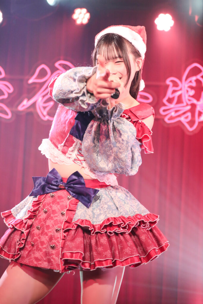 embellir(あんべりー)の恋羽あゆうちゃんをライブ中に撮影した写真。
真っ直ぐにこちらを指さして目を細めつつ笑顔を向けてくれている。
2025年12月13日　渋谷音楽堂　ワンミリにて撮影。